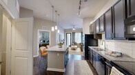 Located at 9015 Eager Rd in Richmond Heights, MO, this well-appointed one-bedroom, one-bathroom residence offers a thoughtfully designed open-concept layout that maximizes every square foot. The kitchen is a standout feature, showcasing rich dark cabinetry that extends to the ceiling, granite countertops, a subway tile backsplash, black appliances including a refrigerator, range, microwave, and dishwasher, and a central island with pendant lighting and seating for two. Track lighting overhead adds a modern touch. The kitchen flows seamlessly into the living room, which is brightened by a glass patio door that invites natural light and provides outdoor access. A ceiling fan enhances comfort in the living area, which offers a relaxed, open ambiance. The bedroom features plush carpeting, a window with soft draping, and direct access to a closet, providing a calm and private retreat. The bathroom is clean and functional, featuring a full tub-shower combination with a curtain rod. Dark hardwood-style flooring runs throughout the main living areas, creating a cohesive and contemporary aesthetic. A dedicated entrance and closet round out the practical layout of this residence.