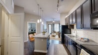 Located at 9015 Eager Rd in Richmond Heights, MO, this well-appointed one-bedroom, one-bathroom residence offers a thoughtfully designed open-concept layout that maximizes every square foot. The kitchen is a standout feature, showcasing rich dark cabinetry that extends to the ceiling, granite countertops, a subway tile backsplash, black appliances including a refrigerator, range, microwave, and dishwasher, and a central island with pendant lighting and seating for two. Track lighting overhead adds a modern touch. The kitchen flows seamlessly into the living room, which is brightened by a glass patio door that invites natural light and provides outdoor access. A ceiling fan enhances comfort in the living area, which offers a relaxed, open ambiance. The bedroom features plush carpeting, a window with soft draping, and direct access to a closet, providing a calm and private retreat. The bathroom is clean and functional, featuring a full tub-shower combination with a curtain rod. Dark hardwood-style flooring runs throughout the main living areas, creating a cohesive and contemporary aesthetic. A dedicated entrance and closet round out the practical layout of this residence.