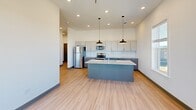 Located at 627 Emma Ave in Springdale, Arkansas, this contemporary 2-bedroom, 2-bathroom unit offers a well-designed single-level layout with clean, modern finishes throughout. Light wood-style flooring flows seamlessly across every room, complemented by crisp white walls, dark baseboards, and gray-toned door frames that lend a cohesive, polished aesthetic.

The open-concept kitchen and living area serves as the heart of the unit, featuring a central island with granite countertops and dual pendant lights overhead. The kitchen is equipped with stainless steel appliances — including a refrigerator, range, and microwave — gray cabinetry, and a subway tile backsplash. A sliding glass door connects the living area to an outdoor space, allowing generous natural light to fill the room.

Both bedrooms are well-proportioned with ceiling fans and large windows that bring in abundant daylight and exterior views. Each bedroom benefits from dedicated closet space, and the primary bedroom connects directly to its own bathroom. Both bathrooms feature granite-topped vanities, gray cabinetry, and light wood-style flooring. A dedicated laundry room and a hallway with louvered closet doors add to the unit's practical storage and functionality. Recessed lighting throughout enhances the bright, modern atmosphere of this thoughtfully designed home.