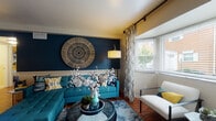 Located at 1361 Presidential Drive in Columbus, Ohio, this single-floor residence showcases a thoughtfully designed interior with a bold and cohesive teal, navy, and yellow color palette carried throughout the space. The living room serves as a striking focal point, featuring a deep navy accent wall adorned with a large woven circular wall art piece, rich hardwood flooring, and a bay window dressed with patterned curtains that invite natural light. An open closet area adjacent to the living space adds practical storage without sacrificing style. The kitchen is equipped with warm wood cabinetry, granite-style countertops, a stainless steel dishwasher, and hardwood floors, offering a functional and inviting cooking environment. The residence includes multiple bedrooms, each distinctly decorated with colorful accent walls — including teal and golden yellow — plush carpeting, ample natural light from well-dressed windows, and open closet storage. One bedroom doubles as a workspace, featuring a stylish desk setup with wall-mounted shelving. The bathroom features classic tile wainscoting, a tub-shower combination, and framed wall art that adds a curated touch. Throughout the home, consistent design choices create a warm, vibrant, and welcoming atmosphere.