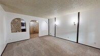 This single-floor, 2-bedroom, 2-bathroom residence offers a functional and characterful layout with a number of distinctive architectural details. The living room is a standout space, featuring a textured ceiling, soft wall-to-wall carpeting, and charming arched doorways that frame the entry and passage into the dining area. Wall sconces add a warm, ambient glow, while dark trim accents provide contrast throughout.

The galley-style kitchen opens to the dining area and is equipped with dark cabinetry, light countertops, a double sink, and white appliances including a range and refrigerator. Wood-look flooring runs through the kitchen, adding warmth and easy maintenance underfoot.

Both bedrooms are carpeted and well-proportioned, with the primary bedroom offering a wood beam accent, wall sconces, and direct access to a private bathroom featuring a soaking tub set beneath an elegant arched alcove with floral wallpaper. The second bathroom mirrors the arched tub surround design with white tile and a vanity with light countertops and wood-tone cabinetry.

Each bedroom benefits from dedicated closet space, and a hallway connects the rooms efficiently. An in-unit laundry area adds everyday convenience. The consistent use of textured ceilings, arched details, and dark trim gives this residence a cohesive and memorable character throughout.