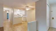 This single-floor unit in Strongsville, Ohio, offers a well-organized layout designed for comfortable everyday living. The kitchen is equipped with white cabinetry, granite-style countertops, a white electric range with an overhead exhaust, and a tile backsplash. Light vinyl flooring runs throughout the kitchen and extends into the adjacent dining or entry area, while a ceiling fan overhead provides additional ventilation. A half-wall partition connects the kitchen to the open living area, which transitions to plush carpeting. The living space features a large sliding glass door dressed with vertical blinds, allowing natural light to fill the room, complemented by a wall-mounted air conditioning unit and baseboard heating. The bedrooms are carpeted and share a similarly neutral palette, each featuring windows with outdoor views and baseboard heating for year-round comfort. Two full bathrooms serve the unit — one featuring a tiled walk-in shower with a framed glass door, and the other offering a full soaking tub with tiled surround. Both bathrooms include tile flooring, a vanity with storage, and a mirrored medicine cabinet. Throughout the unit, neutral tones and consistent finishes create a clean, cohesive aesthetic.