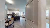 This thoughtfully designed single-floor residence offers a seamless blend of modern style and functional living. The open-concept kitchen is a standout feature, showcasing white cabinetry, granite countertops, a large island with bar seating, subway tile backsplash, stainless steel appliances, and pendant lighting — all flowing naturally into the dining and living areas. Light wood-tone flooring runs throughout the main living spaces, enhancing the bright, airy atmosphere.

The living room is generously proportioned, bathed in natural light from large windows, and opens toward multiple bedrooms. The primary bedroom features plush carpeting, dual windows with views to the exterior, a ceiling fan, and ample room for a full suite of furniture. A second bedroom mirrors the cozy aesthetic with soft carpeting and warm lighting. A flexible den or office space offers wood-look flooring, abundant natural light from multiple windows, and room for a dedicated workspace alongside lounge seating.

The bathrooms are finished with granite vanity countertops, white cabinetry, wood-look tile flooring, and tub-shower combinations framed by elegant large-format tile surround. Every room in this residence reflects a cohesive, contemporary design sensibility with an emphasis on comfort and practicality.