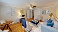 This single-floor residence combines classic architectural details with a clean, cohesive design. Warm hardwood floors run throughout, unifying the living spaces and adding a sense of continuity. Crown molding and ceiling fans with light kits are found in the main living areas, contributing to a polished, timeless aesthetic.

The living room serves as the heart of the home, offering generous proportions and natural light from a large window. Neutral walls provide a versatile backdrop, while the layout easily accommodates multiple seating arrangements. An adjoining area functions as a secondary lounge or flex space, offering additional room for relaxing or working, with direct sightlines into the rest of the unit.

The kitchen has been thoughtfully updated with white shaker-style cabinetry, light stone countertops, and a classic white subway tile backsplash. Black appliances, including a gas range, dishwasher, and microwave, provide a crisp contrast to the bright cabinetry, and tile flooring completes the clean, functional workspace.

The primary bedroom is a comfortable retreat, featuring a ceiling fan, natural light from a window with an outdoor view, and ample wall space. A secondary bedroom offers a cozier feel, with hardwood floors, framed artwork, and its own window, making it well-suited as a guest room or home office.