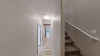 This three-story townhome in North Las Vegas offers four bedrooms and four bathrooms spread across well-organized floors. The ground level houses an attached garage with automatic opener, utility connections, and direct access to a dedicated laundry room equipped with a full-size washer and dryer. The main living floor serves as the heart of the home, featuring an open-plan kitchen and living room. The kitchen is outfitted with warm oak cabinetry, ample counter space, a gas range, built-in microwave, refrigerator, and a stainless steel sink, complemented by a nearby pantry for additional storage. The living area offers light wood-style flooring, neutral toned walls, and a sliding glass door with vertical blinds that fills the space with natural light. Carpeted staircases connect all three levels, while hallways with the same light wood flooring create clean, bright transitions throughout. The bedrooms are finished with light wood-style floors, neutral walls, and closets, including the primary suite with its own private bathroom. Additional bathrooms feature tiled tub-shower combinations and wood-trimmed vanities. Five closets provide generous storage across the home, rounding out a practical and well-appointed layout.