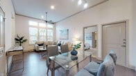 This single-story residence offers two bedrooms and two bathrooms within an open-concept floor plan designed for comfortable everyday living. The living area is a standout space, defined by dramatically high ceilings, a ceiling fan, and a generous bank of tall windows that draw in abundant natural light and views of the outdoors. Wood-style flooring flows throughout the main living areas, anchoring the bright, neutral palette.

The kitchen is well-equipped with dark espresso cabinetry, granite countertops, a subway tile backsplash, stainless steel appliances, and a central island with pendant lighting overhead. A dedicated dining area with a glass-top table sits adjacent to the kitchen, creating a seamless entertaining flow.

Both bedrooms are carpeted and feature ceiling fans, natural light from windows with blinds, and ample space. The primary bathroom offers a dark-cabinet vanity with granite countertops and tile flooring, while the secondary bathroom features large-format marble-style tile, a soaking tub with a shower, and clean white finishes throughout. Together, the spaces create a cohesive, modern aesthetic suited for a variety of lifestyles.