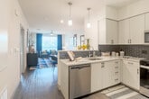 Located at 6670 Emergent Way in San Jose, CA, this well-appointed one-bedroom, one-bathroom residence offers a thoughtfully designed open-concept layout. The kitchen is a standout feature, showcasing crisp white cabinetry, quartz countertops, a bold black subway tile backsplash, stainless steel appliances including a gas range, microwave, dishwasher, and refrigerator, and a peninsula with pendant lighting that flows seamlessly into the dining and living areas. The living room is bright and welcoming, with large windows dressed in rich navy drapes that frame outdoor views and fill the space with natural light. Wood-style flooring runs throughout the main living areas, adding warmth and continuity. The spacious bedroom features plush carpet, a textured accent wall, a ceiling fan, and direct access to a walk-in closet. An arched hallway leads to the full bathroom, which is finished with large-format tile flooring and a full soaking tub surrounded by taupe subway tile. The unit also includes a private balcony, providing an outdoor retreat. Clean lines, modern fixtures, and a cohesive neutral palette with bold accent tones give this residence a polished, contemporary character throughout.
