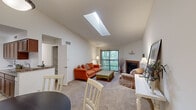 Located at 3984 Brandychase Way in Cincinnati, Ohio, this single-floor residence offers a well-designed layout with a variety of comfortable living spaces. The living room serves as the centerpiece of the home, boasting vaulted ceilings, a large skylight that fills the room with natural light, and a tile-surround fireplace. A sliding glass door opens to a private balcony with views of surrounding greenery. The dining area, positioned adjacent to the living room, features elevated ceilings and a pendant light overhead, creating a defined yet open space. The kitchen is equipped with rich wood cabinetry, stone-look countertops, a double basin sink, and tile flooring. An in-unit washer and dryer are also housed within the kitchen area, alongside a built-in shelving unit for additional storage. The home includes multiple bedrooms, each with plush carpeting and natural light from windows overlooking wooded surroundings. The primary bedroom offers ample closet space, while additional bedrooms provide flexibility for guests or personal use. Throughout the home, neutral wall tones and carpet create a warm, cohesive ambiance, making this a comfortable and practical residence in the Cincinnati area.