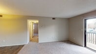 This single-story unit offers a practical and well-organized layout designed for comfortable everyday living. The living area is finished with neutral-toned carpet and features a sliding glass door fitted with vertical blinds, opening to a balcony with outdoor views, allowing natural light to fill the space. A ceiling fan is present in the main living zone, contributing to air circulation throughout.

The kitchen follows a galley-style configuration, equipped with warm wood-toned cabinetry, dark granite-style countertops, a stainless steel sink, and black appliances including a refrigerator, range, and dishwasher. A pendant light fixture accents the adjacent dining area, which features wood-look flooring that extends through the kitchen. A doorway from the kitchen provides direct access to an in-unit laundry area.

The bedrooms are carpeted and finished with neutral walls, ceiling fans with integrated lighting, and windows fitted with blinds that allow natural light. Two full bathrooms serve the unit, each featuring a tub-shower combination with a curtain rod, a toilet, wood-look flooring, and vanity cabinetry. Textured ceilings and consistent neutral tones throughout contribute to a cohesive, understated aesthetic.