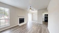 Located at 407 Nottinghill Gate St in Arlington, TX, this single-story home offers a thoughtfully designed layout across a comfortable footprint. The open-plan living and dining area serves as the heart of the home, featuring wood-look plank flooring, a ceiling fan, and a classic fireplace with a white mantel as a focal point. Natural light fills the space through sliding glass doors and windows fitted with blinds, creating a bright and welcoming atmosphere. A pendant light fixture marks the transition into the dining area, which flows seamlessly into the kitchen.

The kitchen is well-appointed with crisp white cabinetry, light quartz-style countertops, a classic subway tile backsplash, and black appliances including a range and over-the-range microwave. A window above the sink adds natural light to the workspace.

The bedroom is a generously sized retreat finished with plush carpeting, two windows that bring in ample natural light, and a ceiling fan overhead. Two doors lead to a dedicated walk-in closet outfitted with built-in shelving, offering practical and organized storage. Neutral tones and textured ceilings carry throughout the home, lending a clean and cohesive aesthetic.