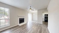 Located at 407 Nottinghill Gate St in Arlington, TX, this single-story home offers a thoughtfully designed layout across a comfortable footprint. The open-plan living and dining area serves as the heart of the home, featuring wood-look plank flooring, a ceiling fan, and a classic fireplace with a white mantel as a focal point. Natural light fills the space through sliding glass doors and windows fitted with blinds, creating a bright and welcoming atmosphere. A pendant light fixture marks the transition into the dining area, which flows seamlessly into the kitchen.

The kitchen is well-appointed with crisp white cabinetry, light quartz-style countertops, a classic subway tile backsplash, and black appliances including a range and over-the-range microwave. A window above the sink adds natural light to the workspace.

The bedroom is a generously sized retreat finished with plush carpeting, two windows that bring in ample natural light, and a ceiling fan overhead. Two doors lead to a dedicated walk-in closet outfitted with built-in shelving, offering practical and organized storage. Neutral tones and textured ceilings carry throughout the home, lending a clean and cohesive aesthetic.