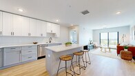 This thoughtfully designed 2-bedroom, 2-bathroom residence offers a well-appointed single-floor layout that balances comfort and modern style. Light wood-look flooring flows throughout the main living areas, complementing a neutral color palette that creates a bright, airy atmosphere.

The open-concept kitchen is a standout feature, equipped with white shaker cabinetry, sleek white quartz countertops, stainless steel appliances, a matte black faucet, and a central island with bar seating — ideal for casual dining and entertaining. The kitchen connects seamlessly to the living room, which is bathed in natural light from a large sliding glass door that opens to a private balcony with open outdoor views.

The primary bedroom offers a comfortable, well-proportioned retreat, while the second bedroom features a large black-framed window with outdoor views and ample space for a home office setup. Both bathrooms are clean and functional, with light cabinetry, white countertops, and tub-shower combinations. Two dedicated closets provide generous storage throughout.

A dedicated laundry room with a full-size side-by-side washer and dryer adds everyday convenience. The overall design reflects a contemporary aesthetic with consistent, quality finishes throughout.