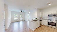 Located at 14055 Central Loop in Woodbridge, VA, this 2-bedroom, 2-bathroom residence offers a well-designed single-level layout with a bright, open feel throughout. The combined kitchen and living area serves as the heart of the home, featuring light hardwood-style flooring, white walls, and a ceiling fan that enhance the airy atmosphere. Large windows and a glass-paneled balcony door flood the space with natural light and provide outdoor views of the surrounding landscaped community.

The kitchen is well-appointed with crisp white shaker-style cabinetry, granite-look countertops, a center island with a sink, stainless steel appliances including a French door refrigerator, range, microwave, and dishwasher, and stylish pendant lighting overhead. The balcony offers a peaceful outdoor retreat overlooking the community grounds.

Both bedrooms are comfortably sized with light flooring, neutral walls, and natural light from windows with blinds. The primary bedroom is a well-proportioned retreat, and the unit includes four closets in total—some featuring wire shelving systems for organized storage. The two bathrooms are clean and functional, with one including a shower/tub combination. An in-unit laundry area adds everyday convenience to this thoughtfully laid-out home.