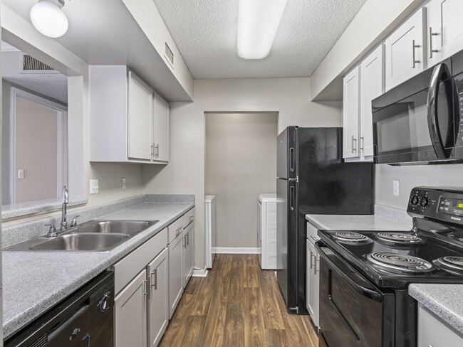 Cook in style with kitchens featuring bright white cabinetry and sleek black appliances, professionally operated by Highlands Vista Group. - Park at Meadow Ridge