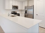 This contemporary single-story residence in San Antonio, Texas, offers 1,130 square feet of thoughtfully designed living space. The home features three bedrooms, including a spacious primary bedroom of 170 square feet, and two full bathrooms. The open-concept floor plan seamlessly integrates the kitchen and living areas, creating a fluid and inviting atmosphere.

The kitchen is a highlight, boasting crisp white cabinetry, stainless steel appliances, and a practical layout. It includes a gas range, built-in microwave, and a refrigerator, all complemented by ample counter space and a breakfast bar.

The bathrooms are pristine and modern, featuring white fixtures, tiled shower/tub combinations, and vanities with storage. Light-colored wood-look flooring runs throughout the main living areas, while plush carpeting adds comfort to the bedrooms.

Large windows in each room allow for abundant natural light, enhancing the home's bright and airy feel. The neutral color palette, predominantly white walls, and ceilings create a clean, contemporary aesthetic that serves as a blank canvas for personal decorating styles.

Storage solutions include closets in the bedrooms and hallway. The property's layout efficiently utilizes the available space, making it an ideal choice for those seeking a low-maintenance yet comfortable living environment in the San Antonio area.