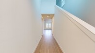 This well-appointed two-story home offers four bedrooms and four bathrooms across two thoughtfully designed floors. The main level features an open-concept kitchen and living area with light wood flooring that flows seamlessly throughout. The kitchen is a standout, showcasing rich dark wood cabinetry, granite countertops, a center island with a built-in sink, and stainless steel appliances including a gas range, microwave, and refrigerator with recessed lighting overhead. The living area is bright and airy, with multiple windows inviting natural light and a ceiling fan adding comfort. A dedicated laundry room with overhead cabinetry and wood-look flooring adds everyday convenience on the main floor. Upstairs, the secondary level houses the remaining bedrooms, each carpeted and equipped with ceiling fans and windows that offer outdoor views. The primary bedroom includes a well-organized walk-in closet with double hanging rods and shelving. The primary bathroom is elegantly finished with warm wood-tone vanity cabinetry, granite countertops, light wood flooring, and a glass-enclosed tile shower. Three hallways connect the spaces across both levels, with a staircase featuring clean white railings and a soaring open ceiling that adds an impressive sense of vertical space throughout.