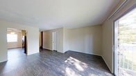 This two-floor space offers a straightforward and functional layout designed for comfortable everyday living. The main living area is open and well-proportioned, finished with rich, dark hardwood flooring that adds warmth and a sense of depth to the room. Neutral beige-toned walls provide a versatile backdrop that pairs well with a variety of furnishing styles, while white baseboards offer a clean contrast throughout. Natural light filters into the living area, casting gentle patterns across the floor and contributing to an airy, welcoming atmosphere. A textured white ceiling adds subtle visual interest without overpowering the overall simplicity of the space. A white interior door is visible, leading to additional rooms or utility areas, hinting at a thoughtful and organized floor plan. The open nature of the main level provides a sense of spaciousness, making it easy to arrange furniture to suit individual needs. Spanning two floors, this space offers ample room for both living and private quarters, making it well-suited for a range of occupants. The clean, move-in-ready condition of the space, combined with its classic finishes and neutral palette, ensures a solid foundation for personalization and interior design.