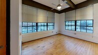 This 410 sq ft apartment in downtown Winston-Salem combines modern amenities with industrial charm. The space features a single bedroom, bathroom, living area, and hallway. Large windows provide stunning city views and abundant natural light, complementing the warm wooden floors. The bathroom boasts contemporary fixtures, including a granite countertop and spacious shower. High ceilings with exposed beams add character, while a ceiling fan ensures comfort. The bedroom includes a built-in closet for storage. This efficient layout maximizes space, creating a cozy yet functional urban dwelling.