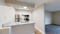 This single-floor residence offers a thoughtfully designed layout that blends modern finishes with comfortable, functional living. The kitchen serves as a central highlight, featuring granite-look countertops, white shaker-style cabinetry, a subway tile backsplash, and a full suite of stainless steel appliances including a refrigerator, electric range, and over-the-range microwave. A peninsula with an integrated sink provides additional prep space and opens naturally to the adjoining living and dining areas.

The living areas are finished with durable wood-look flooring and neutral warm-toned walls, creating a bright and cohesive atmosphere. Ceiling fans offer both light and air circulation, while a sliding glass door in the entry area leads to a private balcony, bringing in natural light. The bedroom is finished with plush carpeting, a ceiling fan, and a window with outdoor views, offering a quiet and comfortable retreat.

The bathroom features a tub-shower combination with elegant marble-style tile surround, wood-look flooring, and open shelving. Conveniently located in-unit laundry with built-in shelving above adds practical storage. Throughout the space, clean white trim, textured ceilings, and a consistent neutral palette create a polished, move-in-ready environment.
