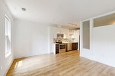 Located at 2900 Main Line Blvd in Alexandria, Virginia, this modern one-bedroom, one-bathroom unit offers a thoughtfully designed layout across a single floor. Light-toned hardwood flooring flows throughout the space, lending a clean, cohesive aesthetic. The open-plan kitchen and living area serves as the heart of the unit, featuring a contemporary kitchen equipped with stainless steel appliances—including a range, microwave, and dishwasher—two-tone cabinetry with white upper cabinets and rich dark lower cabinets, a mosaic tile backsplash, and ample counter space. Track and pendant lighting illuminate the kitchen and living area, enhancing the bright, airy atmosphere. A well-lit hallway connects the main living space to the private rooms, and includes an in-unit washer and dryer for added convenience. The bedroom is a tranquil retreat featuring clerestory windows that allow diffused natural light to filter in, complemented by a ceiling fan. The living area opens to a private balcony through sliding glass doors, offering pleasant outdoor views of the surrounding greenery. The bathroom is finished with large-format tile flooring, a walnut-toned vanity with a white countertop, and a full tub and shower combination. A dedicated closet provides practical storage within the unit.
