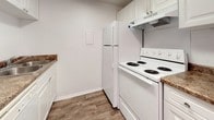 Parks Edge Unit #2 is a two-bedroom, two-bathroom single-floor residence designed with functionality and simplicity in mind. The layout, visible in the overhead floor plan, arranges the living spaces efficiently, with clearly defined areas for living, sleeping, and bathing connected by a straightforward corridor.

The bedrooms feature neutral carpet flooring and white walls, providing a clean, versatile backdrop. Each room receives natural light through standard windows, with views of the surrounding neighborhood. Generous closet space is present, including a double-door closet with a full-width hanging rod, offering ample storage.

The kitchen is equipped with white cabinetry, dark-toned countertops, a full-size refrigerator, and an electric range with overhead ventilation. Wood-look vinyl flooring runs through the kitchen and extends into the hallways and wet areas, providing a cohesive and durable surface throughout non-carpeted zones.

Both bathrooms maintain a clean, all-white aesthetic. One features a shower-tub combination with a curtain rod and a vanity, while the second bathroom provides a toilet and additional fixtures. Both bathrooms feature the same wood-look flooring consistent with the rest of the unit.