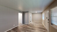 This single-story, 2-bedroom, 1-bathroom unit in Lafayette, Louisiana offers a clean, updated interior with a cohesive neutral color palette and durable vinyl plank flooring throughout. The living area greets residents at the front entry, where multiple windows fitted with blinds allow natural light to fill the space, complemented by a ceiling fan overhead. The open layout connects the living area to the kitchen, which features white shaker-style cabinetry, granite-look countertops, a double-basin stainless steel sink, and a skylight that brightens the workspace. Both bedrooms are generously proportioned, each dressed in neutral gray tones and dark-toned vinyl plank flooring that adds warmth and contrast. A connecting hallway leads between the two bedrooms, maintaining a logical and efficient flow. The bathroom is outfitted with white tile wainscoting, a tub-shower combination, a white vanity, and matching brushed nickel hardware. Textured ceilings and white baseboards are consistent throughout, lending the unit a uniform, well-maintained appearance. The overall ambiance is tidy, neutral, and move-in ready, suited for comfortable everyday living.