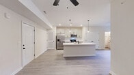 Located at 15 Millswood Dr in Clarksville, TN, this well-appointed single-story home offers a thoughtfully designed open-concept layout. The combined kitchen and living area serves as the heart of the home, featuring light wood-look luxury vinyl plank flooring, recessed lighting, and a ceiling fan that enhances airflow and comfort. The kitchen is a standout, outfitted with crisp white shaker-style cabinetry accented by matte black hardware, a classic white subway tile backsplash, gleaming white quartz countertops, and a full suite of stainless steel appliances including a French door refrigerator, range, and built-in microwave. A generously sized center island with an integrated sink and pendant lighting provides both additional prep space and a natural gathering spot. The living area opens toward French doors, allowing natural light to flow through. The spacious primary bedroom features plush carpeting, a ceiling fan, and a natural light-filled window. A dedicated closet offers ample storage. Both bathrooms are clean and functional, with one featuring a tiled tub/shower combination. Neutral tones and modern finishes throughout lend the home a fresh, cohesive aesthetic.