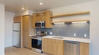 Located at 360 W 200 S in the heart of downtown Salt Lake City, this thoughtfully designed studio offers a contemporary urban living experience on a single floor. The open-plan layout seamlessly integrates the living, dining, and kitchen areas, all unified by light-toned hardwood flooring that enhances the sense of brightness throughout.

The kitchen is a standout feature, finished with warm natural wood cabinetry, crisp white countertops, and a cool-toned subway tile backsplash. Stainless steel appliances — including a range, microwave, refrigerator, and dishwasher — provide full functionality, while open shelving adds an airy, modern touch.

Floor-to-ceiling windows flood the living area with natural light and frame impressive views of the Salt Lake City skyline and the Wasatch Mountains beyond. Exposed ductwork and adjustable track lighting lend an industrial-modern character to the space.

The bathroom is well-appointed with a vessel sink atop a wood vanity, an illuminated frameless mirror, and a full tub with tiled surround. Two closets provide practical storage. Clean lines, neutral tones, and quality finishes throughout create a cohesive, contemporary aesthetic well-suited to urban living.