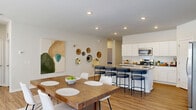 Located at 1909 Boynton Way in Bolivia, NC, this single-story, 3-bedroom, 2-bathroom home offers a thoughtfully designed open-concept floor plan. The combined kitchen and living area serves as the heart of the home, showcasing warm wood-look flooring, recessed lighting, and a seamless flow between spaces. The kitchen is outfitted with crisp white cabinetry, granite countertops, stainless steel appliances, and a large island with bar seating — ideal for casual dining and entertaining. An adjacent dining area features direct access to the living room, which opens to the outdoors through a sliding glass door, inviting an abundance of natural light. A clean, wide hallway connects the common areas to the private quarters, where three carpeted bedrooms provide comfortable retreats. The generously sized primary bedroom benefits from natural light and easy access to a well-appointed bathroom with a floating vanity. Additional bedrooms are bright and versatile, served by closets with wire shelving systems. The two bathrooms are finished with wood-look flooring and clean, neutral palettes. Throughout the home, a light and airy aesthetic is maintained with soft neutral tones, creating a welcoming and cohesive atmosphere.