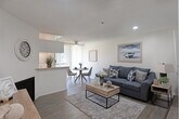 Located in the Westwood neighborhood of Los Angeles, this single-floor unit at 424 Kelton Ave offers a thoughtfully designed layout with a seamless flow between living, dining, and sleeping spaces. The open-concept living and dining area is anchored by warm wood-style flooring, a textured ceiling, and a ceiling fan that enhances air circulation. A cozy fireplace adds character to the living space, while vertical blinds frame access to a private balcony, allowing natural light to fill the room. A pass-through counter connects the living area to the galley kitchen, which features white cabinetry, granite-style countertops, a double stainless steel sink, and white appliances including a range and refrigerator — all set against clean, bright walls. The generously sized bedroom accommodates multiple beds and opens into a connecting hallway with ample closet space, lending a sense of flexibility and openness. The bathroom is neatly finished with white cabinetry, granite-style countertops, a large mirror, and hardwood-style flooring, with a separate water closet providing added privacy. Throughout the unit, consistent wood-style flooring, recessed lighting, and a neutral color palette create a cohesive and inviting atmosphere ideal for comfortable urban living.