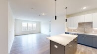 Located at 8680 State Line Rd in Leawood, KS, this modern single-floor residence offers three bedrooms, four bathrooms, and a thoughtfully designed open-concept layout. The kitchen serves as a focal point, showcasing two-tone cabinetry in white and slate blue, a quartz-topped island with pendant lighting, stainless steel appliances, and a tasteful tile backsplash — all flowing seamlessly into a bright, open living area with light wood-style flooring and large windows that draw in natural light and outdoor views of the surrounding landscape. The bedrooms are carpeted for comfort, with multiple rooms featuring wide windows that frame scenic wooded views; one bedroom includes a ceiling fan and another opens to a private balcony. The primary bedroom is generously sized and accompanied by a walk-in closet outfitted with multi-level wire shelving for ample storage. The four bathrooms include well-appointed designs with clean white tile, tub-shower combinations with brushed nickel fixtures, and pedestal sinks. A dedicated laundry room with a stacked washer and dryer adds everyday convenience. Throughout, the space maintains a clean, contemporary aesthetic with neutral tones, crisp white walls, and durable modern finishes.