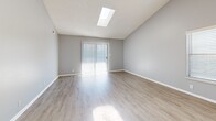 Located at 2360 W 76th Ave in Denver, CO, this single-floor, three-bedroom, two-bathroom home offers a practical and comfortable layout. The living room is a standout space, featuring vaulted ceilings, a skylight that fills the room with natural light, light-toned luxury vinyl plank flooring, and a sliding glass door that connects the interior to the outdoors. The kitchen is well-appointed with white shaker-style cabinetry, granite-look countertops, black appliances including an electric range and dishwasher, and matching light wood flooring that flows throughout the main living areas. A dedicated laundry area and hallway provide additional functionality. Each of the three bedrooms is finished with neutral carpet and soft gray walls, offering a calm and restful atmosphere. The primary bedroom includes a sliding-door closet, while the additional bedrooms also feature dedicated closet spaces. Both bathrooms are finished consistently, with white vanities, granite-look countertops, tub-shower combinations with tile surrounds, and light wood flooring. The home's cohesive gray and white color palette, combined with clean finishes throughout, creates a neat and move-in-ready living environment.