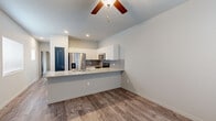 Located on Adventure Way in Colorado Springs, CO, this well-designed one-bedroom, two-bathroom unit offers a smart and functional single-floor layout. The open-concept kitchen serves as the heart of the space, showcasing granite countertops, a peninsula with an undermount sink, white cabinetry, a gray tile backsplash, and a full suite of stainless steel appliances including a French door refrigerator, electric range, over-the-range microwave, and dishwasher. Wood-look plank flooring and a ceiling fan complement the bright, neutral living area adjacent to the kitchen. The bedroom features plush carpeting, a wall-mounted mini-split HVAC unit for personalized climate control, a natural light-admitting window with blinds, and a closet with a distinctive teal panel door. Two bathrooms provide added convenience, with one featuring a granite-topped vanity, wood-look tile flooring, and a full tub-shower combination. A dedicated hallway area houses a stacked washer and dryer along with an electrical panel. Two closets offer ample storage throughout. The consistent use of granite surfaces and coordinating finishes gives the space a cohesive, modern aesthetic.