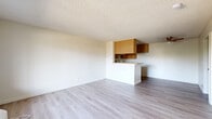 Located at 249 W Alameda Ave in Burbank, CA, this one-bedroom, one-bathroom unit offers a practical and well-organized layout across a single floor. The open-concept living room and kitchen area is finished with light wood-style laminate flooring and neutral cream walls, creating a bright, clean atmosphere. A window in the living area allows natural light to filter in, offering a view of the surrounding neighborhood. The kitchen is enclosed on three sides with warm oak cabinetry extending to the ceiling, providing ample storage. A peninsula with a built-in countertop separates the kitchen from the living space, offering both a visual divider and additional workspace. The kitchen includes a gas range with overhead ventilation and a sink positioned along the side wall. The bedroom is a comfortable size, carpeted for warmth, and features its own dedicated walk-in closet with dual hanging rods and an overhead shelf, maximizing storage capacity. The full bathroom includes a shower and tub combination set against clean white tile surround, with a toilet and towel bar. Throughout the unit, textured ceilings and neutral tones contribute to a consistent, understated aesthetic. A ceiling fan is present in the living area near the kitchen, adding functional comfort to the space.