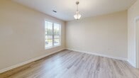 Located at 14112 Castle Top Ct in Fountain Inn, SC, this single-story home offers a well-designed layout finished with consistent, light-toned wood-look flooring and neutral warm beige walls throughout, creating a cohesive and inviting atmosphere.

The kitchen serves as a functional centerpiece, featuring rich cherry-toned cabinetry with ample upper and lower storage, granite countertops, and a full suite of stainless steel appliances including a refrigerator, electric range, and built-in microwave. A peninsula with an extended granite overhang provides casual seating and separates the kitchen from the adjacent living and dining areas. Pendant lighting and crown molding add refined detail to the space.

Living and dining areas are generously proportioned, with large windows fitted with white plantation-style blinds that allow abundant natural light. A glass-paneled exterior door opens to the outside, further enhancing brightness. Crown molding accents the main living area.

The bathroom includes a double-sink vanity topped with granite, warm wood cabinetry, and large-format tile flooring. A dedicated laundry area with wire shelving and washer/dryer hookups adds everyday convenience. Bedrooms are well-sized with ample natural light from windows.