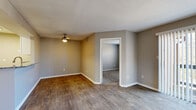 This single-floor residence offers a thoughtfully designed layout with a neutral taupe color palette, white trim, and a blend of durable wood-style flooring and plush carpeting throughout. The living area is bright and open, featuring a ceiling fan with light fixture, a sliding glass door leading to a private balcony, and an adjacent window that draws in natural light and outdoor views. The entry foyer provides convenient access to the main living spaces and includes a coat closet nearby.

The kitchen is a standout feature, showcasing granite countertops with an integrated sink on a peninsula-style breakfast bar, white shaker cabinetry, and a full suite of stainless steel appliances including a refrigerator, range, and over-the-range microwave. Wood-style flooring continues through this space, adding warmth and cohesion.

The bedrooms are carpeted for comfort, each offering good natural light through blinds-fitted windows. The primary bedroom is particularly notable for its dual closets, providing generous storage. A dedicated in-unit laundry area houses a full-size top-loading washer and dryer with overhead shelving.

The bathroom is finished with gray shaker-style cabinetry, granite countertops, a large vanity mirror, and a shower-tub combination, complemented by wood-style flooring that ties the space together cohesively.