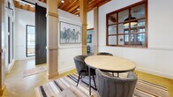 Located at 2500 Gault Way Dr in Summerville, SC, this single-floor amenity space blends modern design with warm, natural materials to create an inviting and functional environment. The interior is immediately distinguished by its striking tongue-and-groove wood ceiling, which adds warmth and texture overhead, while polished concrete floors ground the space with an industrial-chic aesthetic.

Tall, light-filled windows with bold black frames line the walls, flooding the interior with natural light and offering clear views of the surrounding residential community, including lush palm trees and vibrant blue-accented buildings. Steel-framed glass partition doors further enhance the open, airy feel while elegantly delineating different areas of the space.

Substantial wood-clad columns punctuate the main gathering area, lending a sense of architectural character and definition. A round dining table surrounded by plush upholstered chairs serves as a central meeting point, set atop a striped area rug and complemented by curated artwork, including a notable equestrian painting. A barn-style sliding door adds a rustic touch.

A more private seating area features a wall-mounted flat-screen display alongside a round table and chairs, making it well-suited for presentations or small group gatherings. Throughout, the design balances comfort and functionality, creating a welcoming space ideal for community interaction and collaboration.