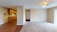 This single-floor residence offers a practical and functional layout designed for comfortable everyday living. The open living area serves as the central gathering space, featuring neutral-toned carpet, a ceiling fan with a light fixture, and a large sliding glass door fitted with vertical blinds that fills the room with natural light and provides views of the surrounding greenery outside.

The galley-style kitchen is positioned adjacent to the living area and features warm wood-toned cabinetry, granite-look countertops, hardwood-style flooring, and stainless steel appliances including a refrigerator and dishwasher, offering an efficient and well-equipped cooking space.

The bedrooms are carpeted and bathed in natural light through windows fitted with horizontal blinds. Each room includes a ceiling fan and light fixture, providing adequate ventilation and ambient lighting. Closet access is available in at least one bedroom.

The bathroom is cleanly finished with white subway tile lining the soaking tub surround, accented by a decorative band of earth-toned diagonal tiles near the top. Hardwood-style flooring, a granite-top vanity, and brushed nickel hardware complete the space. Throughout the unit, a consistent neutral color palette and textured ceilings contribute to a cohesive, understated aesthetic.