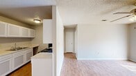 Located at 867 Fendley Dr in Conway, Arkansas, this efficient single-floor, one-bedroom, one-bathroom unit offers a practical and comfortable layout. The open-concept main living area seamlessly combines the kitchen, dining, and living spaces into one cohesive zone. The kitchen is equipped with white cabinetry, a gas range, black appliances including a refrigerator and microwave, a sink with counter space, and a peninsula that separates it from the living and dining area. Wood-look laminate flooring runs throughout the kitchen and living spaces, providing a clean, easy-to-maintain surface. The living area features a ceiling fan with a light fixture, adding both comfort and functionality, with access to a sliding glass door that brings in natural light. A hallway connects the main living area to the private spaces of the unit. The bedroom is generously proportioned, finished with soft wall-to-wall carpet, a ceiling fan, a window with blinds, and two closets, offering ample storage. The bathroom includes a single-sink vanity with cabinet storage, a toilet, and a full tub/shower combo. A textured ceiling is present throughout the unit, contributing to its classic residential character.