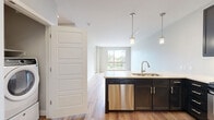 Located at 2100 W Littleton Blvd in Littleton, CO, this well-appointed 2-bedroom, 2-bathroom residence offers a thoughtfully designed single-level layout. The open-concept kitchen and living area serves as the heart of the home, featuring rich dark cabinetry, a bold blue peninsula with a white quartz countertop, stainless steel appliances including a gas range, microwave, and refrigerator, a tile backsplash, and pendant lighting. Light hardwood-style flooring flows throughout the main living areas, complementing the neutral warm-toned walls. Large sliding and picture windows flood the living space with natural light and frame views of the surrounding neighborhood. The spacious primary bedroom includes plush carpeting, a ceiling fan, a generous picture window, and a walk-in closet with built-in shelving and hanging rods. The second bedroom also features carpet and a sliding panel closet. Both bathrooms are finished with white subway tile, a decorative mosaic border, and light tile flooring. One bath offers a glass-enclosed tub and shower combination with stainless grab bars, while the other includes a full tub/shower with a curved rod and dark vanity cabinetry. The overall ambiance is clean, modern, and move-in ready.