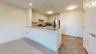 Located at 2000 NE Coronado Dr in Blue Springs, Missouri, this 1-bedroom, 1-bathroom unit offers a thoughtfully designed single-floor layout that maximizes functionality and comfort. The kitchen serves as the centerpiece of the home, boasting crisp white shaker-style cabinetry, granite countertops, and a full suite of stainless steel appliances including a range, dishwasher, microwave, and refrigerator. A peninsula-style breakfast bar separates the kitchen from the living area, creating an open and connected feel throughout the main living space. Wood-style plank flooring runs through the kitchen and bathroom areas, while plush carpeting adds warmth to the living room and bedroom. The living area benefits from natural light streaming in through French doors, which provide an inviting connection to the outdoors. The bedroom is a comfortable, carpeted retreat featuring a double-door closet and a window with outdoor views, allowing for plenty of natural light. The bathroom continues the cohesive design aesthetic with matching granite countertops and wood-style flooring. Neutral, warm tones throughout the unit create a clean and welcoming ambiance, making this an efficiently designed space ideal for everyday living.