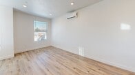 Located at 565 S Redwood Rd in Salt Lake City, UT, this contemporary three-story townhouse offers a well-organized layout across three distinct levels. The ground floor features a spacious garage with concrete flooring, recessed lighting, and a transom window that allows natural light to filter in, along with a private entrance.

The main living level is the heart of the home, combining a living room, dining area, and kitchen in an open-concept arrangement. Light wood-tone cabinetry, stainless steel appliances including a refrigerator, electric range, and microwave, and a central island with a sink define the modern kitchen. Light hardwood flooring and recessed lighting run throughout, while a wall-mounted mini-split system ensures year-round climate control.

The upper floor houses the two bedrooms, each featuring light carpeting or hardwood floors and individual mini-split units. The primary bedroom benefits from multiple windows that invite generous natural light and outdoor views. A stacked washer and dryer unit offers in-unit laundry convenience. With four bathrooms distributed across the floors, two closets, and connecting hallways and staircases, this townhouse delivers a practical and polished living experience within a modern multi-unit community.