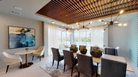Located along the scenic Boardwalk Trail in Austin, TX, this single-floor space is a thoughtfully designed gathering venue that blends modern aesthetics with functional elegance. The centerpiece of the space is a generously sized dining area anchored by a large rectangular table surrounded by upholstered chairs, set atop a layered area rug. Overhead, a striking slatted wood ceiling treatment adds warmth and architectural interest, complemented by two dramatic mid-century-style Sputnik chandeliers that cast ambient light throughout the room. Floor-to-ceiling windows line one wall, flooding the interior with natural light and framing panoramic waterfront views of the surrounding greenery and water — a defining feature of the space.

A teal accent wall with a wall-mounted television and a secondary seating nook with a marble-topped bistro table offer a more intimate setting within the same open layout. The space also includes a dedicated wet bar area, complete with dark cabinetry, stainless steel appliances, a sink, and a sculptural 3D-textured tile backsplash with integrated shelving and accent lighting. Entry is through a glass-paneled door, reinforcing the space's open, airy character throughout.