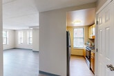 Located in Boston, MA, this one-bedroom, one-bathroom residence offers a well-organized single-floor layout with light wood-style flooring and neutral tones throughout. The open-concept living and dining area is generously proportioned, featuring multiple windows that allow abundant natural light and views of the surrounding urban streetscape. A textured ceiling adds character to the airy common areas.

The kitchen is equipped with warm maple-toned cabinetry, granite-look countertops, stainless steel appliances including a refrigerator and range, and a window overlooking the neighborhood — providing both functionality and brightness.

The bedroom is a comfortable retreat, featuring wood-style flooring, soft neutral walls, and its own closet with classic panel doors. A hallway with a wall sconce connects the main living spaces and provides access to additional closets — four in total throughout the unit, offering excellent storage.

The bathroom includes a full tub/shower combination with tiled surround and clean white fixtures. A central hallway connects all rooms efficiently, making the layout practical and easy to navigate. This residence combines comfortable proportions with a clean, updated aesthetic in a sought-after Boston location.
