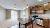 This well-appointed 2-bedroom, 2-bathroom residence at Cedar Grove Parkway in Eagan, MN offers a thoughtfully designed single-floor layout with a seamless blend of function and style. The open-concept kitchen and living area serves as the heart of the home, featuring rich hardwood-style flooring, crown molding, and a pendant-lit kitchen island with a dark granite countertop. The kitchen is fully equipped with stainless steel appliances — including a range, microwave, dishwasher, and refrigerator — complemented by warm wood cabinetry and granite countertops. The adjacent living area is bright and airy, with sliding glass doors that invite natural light and outdoor views. Both bedrooms are carpeted and generously sized, with the primary bedroom offering ample space and access to its own bathroom. The two bathrooms are finished with stone-tile flooring and dark vanities topped with granite. One bathroom features a walk-in shower with grab bar, while the other includes a full tub-shower combination. Storage is plentiful throughout, with five closets — including spacious walk-in closets fitted with wire shelving systems. An in-unit laundry area adds everyday convenience, rounding out this well-equipped Eagan residence.