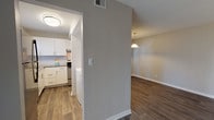 This single-floor residence offers a thoughtfully designed layout with a cohesive, neutral color palette and a blend of flooring materials that define each living area. The kitchen is a standout feature, outfitted with crisp white shaker-style cabinetry, granite countertops, a classic subway tile backsplash, and stainless steel appliances including a dishwasher and range. A double-basin sink is positioned beneath a window, providing natural light and a view of outdoor greenery. The living and dining areas are finished with rich, dark hardwood-style flooring and are connected by an open corridor illuminated by a pendant light fixture, lending a warm and welcoming ambiance. Sliding glass doors in multiple rooms bring in abundant natural light and offer direct outdoor views, further enhancing the sense of openness. The bedrooms feature plush carpeting, neutral walls, and large windows or sliding doors dressed with blinds, creating comfortable and versatile spaces. The bathrooms are well-appointed with granite-topped white vanities and hardwood-style flooring. One bathroom features a shower-tub combination, while another includes accessible grab bars, a clean white vanity, and a tiled shower area. The textured ceilings and clean white trim throughout provide a polished, move-in-ready finish.
