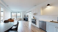 Located at 5005 Old Cedar Lake Rd in St. Louis Park, MN, this modern residence offers four bedrooms and two bathrooms across a single thoughtfully designed floor. The open-concept kitchen and living area serves as the heart of the home, featuring white shaker cabinetry, a white tile backsplash, stainless steel appliances including a gas range and dishwasher, and warm pendant lighting. Light wood-tone flooring flows seamlessly throughout the main living areas, enhancing the bright, airy atmosphere. The living room is anchored by large sliding glass doors that invite natural light and provide access to an outdoor balcony with outdoor views. The bedrooms are carpeted for comfort, with the primary bedroom offering a dedicated walk-in closet with wire shelving. The bathrooms are finished with white cabinetry, matte black fixtures, gold hardware accents, and wood-look tile flooring, lending a clean, contemporary feel. A dedicated in-unit laundry area houses a stacked Samsung washer and dryer. Clean white walls, modern black door hardware, and louvered laundry closet doors contribute to the cohesive, minimalist aesthetic found throughout the entire residence.