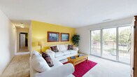 Located at 801 Sherwood Lake Drive in Schererville, Indiana, this two-bedroom, one-bathroom single-floor residence offers a well-organized and comfortable layout. The living room is a standout space, featuring a bold yellow accent wall, soft carpeting, a ceiling fan, and sliding glass doors that open to a private balcony with outdoor views, filling the room with natural light. Adjacent to the living area is a dedicated dining room with a closet and wall art, providing a defined space for meals. The galley-style kitchen is efficiently designed with warm wood cabinetry, white countertops, a double sink, tile flooring, and white appliances, along with access to the in-unit laundry area. The primary bedroom is generously sized, featuring large sliding glass doors that invite natural light and outdoor views, complemented by plush carpeting. The second bedroom offers a serene retreat with a sage green accent wall, a bright window, and soft carpet. Both bedrooms are served by two sizable closets, including a walk-in closet with dual hanging rods. The shared bathroom features tile flooring, a vanity with storage, and a shower/tub combination with a drop ceiling panel. Overall, the home presents a warm and functional ambiance throughout.