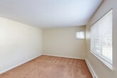 Located at 11 Anthony Rd in New London, CT, this multi-floor home offers two bedrooms, two bathrooms, and a well-distributed layout across three levels. The exterior presents classic New England-style siding in a neutral gray tone, set within a well-maintained community with open green lawns and a private white-railed deck that overlooks the surrounding grounds. The main living level features light hardwood-style flooring and a semi-open kitchen equipped with rich cherry wood cabinetry, dark granite countertops, black appliances including a refrigerator, dishwasher, and range, plus a convenient breakfast bar that connects to the dining area. The bathrooms are finished in a clean, bright style with white vanities, full tub-shower combos, and light wood flooring. Both bedrooms are carpeted in warm neutral tones and include baseboard heating and blinds-fitted windows that allow natural light. Closets are generously sized with built-in hanging rods. The basement level provides additional utility space with painted concrete floors, suitable for storage or utility purposes. A dedicated laundry area and multiple staircases and hallways ensure easy navigation throughout. This home delivers a practical and comfortable living environment in a quiet residential setting.