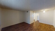Located at 4902 E Thomas Rd in Phoenix, Arizona, this single-floor unit offers a practical and straightforward layout designed for comfortable everyday living. The main living area is open and inviting, featuring rich wood-style flooring that extends throughout the space, white walls, and a textured ceiling. A distinctive painted brick accent wall adds a subtle architectural character to the living room, which also benefits from a front-facing window fitted with vertical blinds that allow natural light to filter in. A ceiling fan provides additional comfort overhead.

The kitchen is efficiently designed in an L-shaped configuration, outfitted with white cabinetry, light countertops, a double stainless steel sink, a white gas range, a dishwasher, and a refrigerator. A window above the sink brings in additional natural light, and tile backsplash details add a clean, classic finish.

The bathroom is compact and functional, featuring a combined tub and shower enclosure in white, a toilet, and a ceiling light fixture, with wood-style flooring consistent with the rest of the unit. HVAC vents are present throughout, ensuring climate control — a key consideration in the Phoenix, Arizona environment. Overall, the unit presents a clean, move-in ready space with cohesive finishes and a logical flow between rooms.
